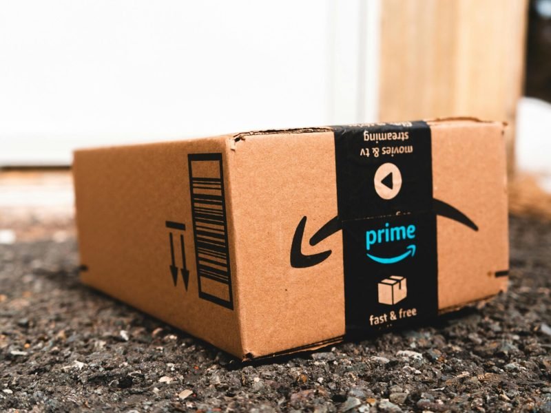 A cardboard box marked with Prime logo placed outside on a porch, ready for delivery.