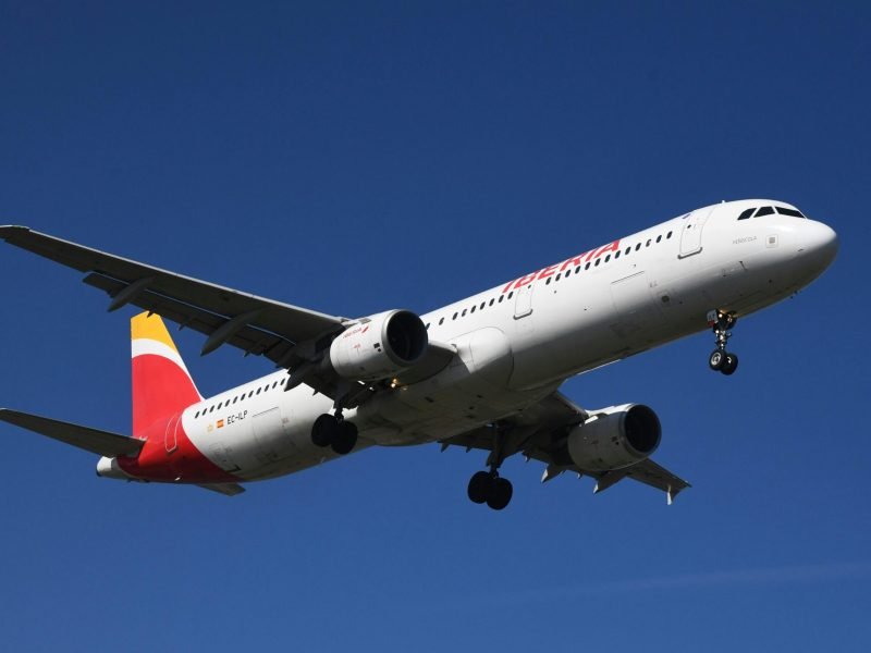 Airplane soaring against a clear blue sky in Geneva, Switzerland.