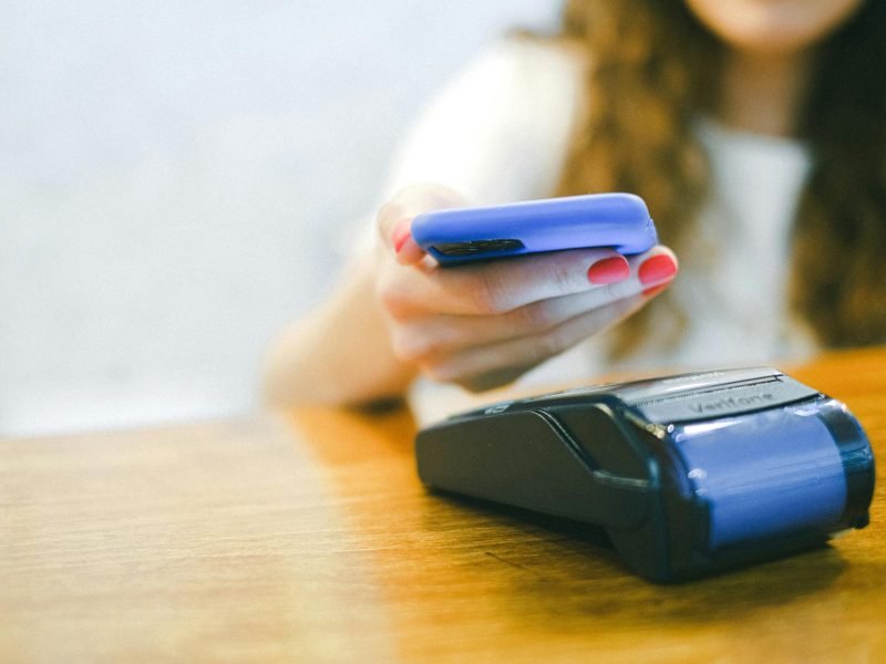 Close-up of a woman making a contactless payment using a smartphone over a card reader