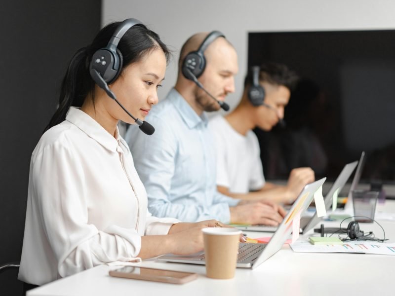 Customer service agents efficiently handle calls using laptops and headsets in a modern office.